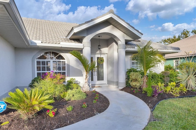 property entrance featuring a tiled roof and stucco siding