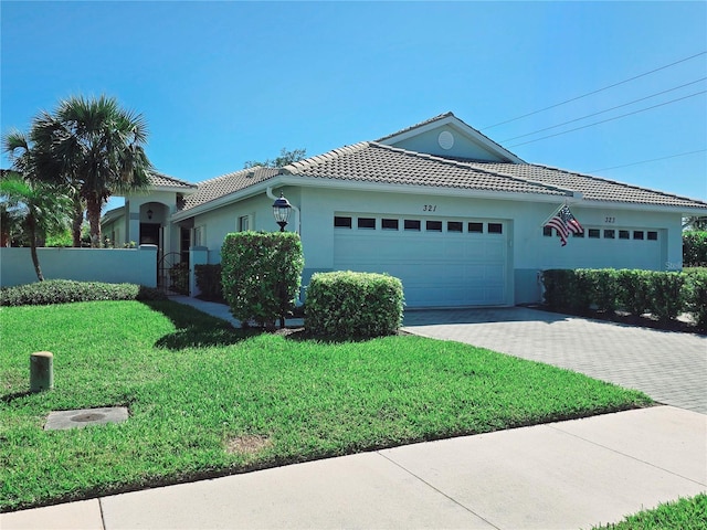 single story home featuring a front yard, stucco siding, a garage, a tiled roof, and decorative driveway