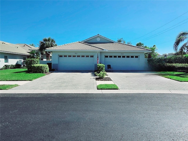 single story home with stucco siding, driveway, a tile roof, and an attached garage