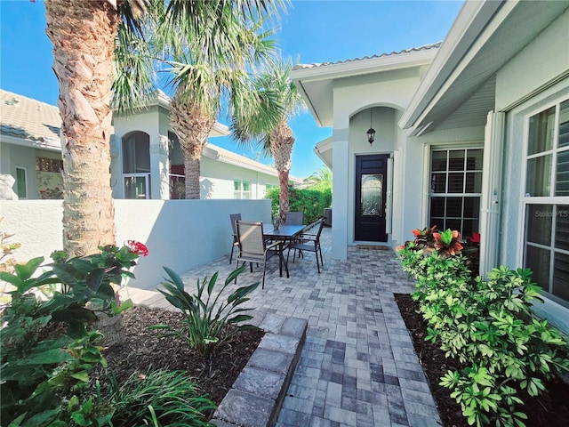 doorway to property featuring a patio area, outdoor dining space, stucco siding, and fence