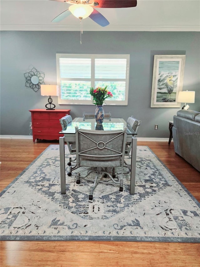 dining space featuring baseboards, wood finished floors, a ceiling fan, and ornamental molding