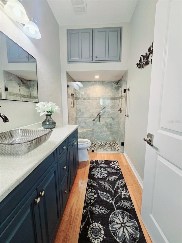 bathroom with visible vents, toilet, a stall shower, wood finished floors, and vanity