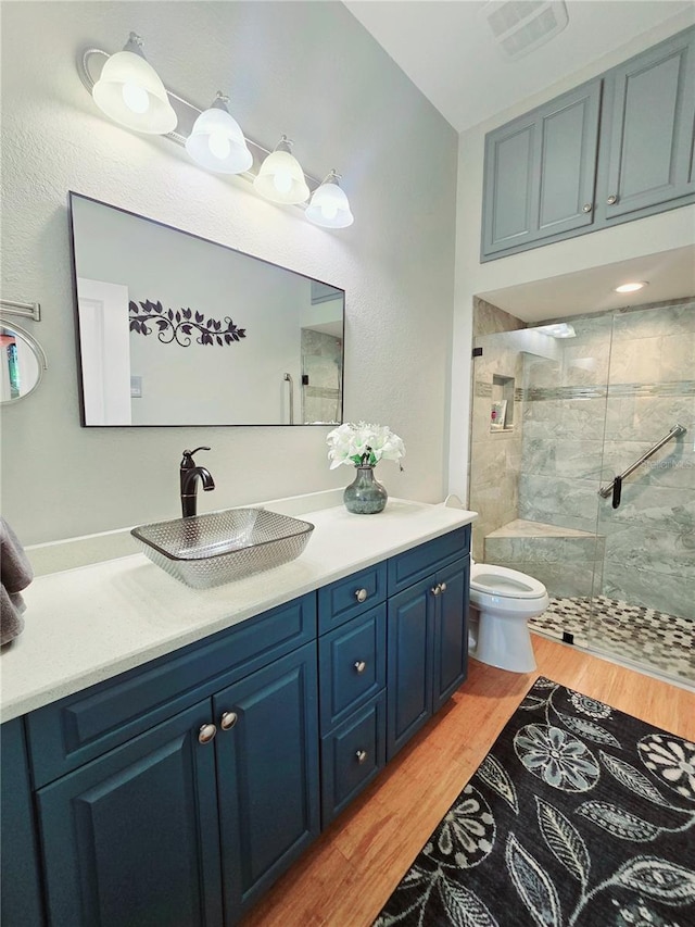 bathroom featuring visible vents, toilet, a stall shower, wood finished floors, and vanity