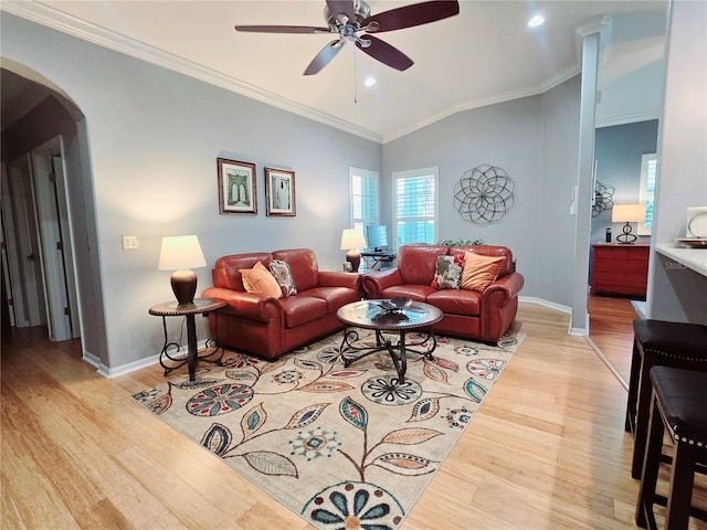 living room with crown molding, arched walkways, light wood finished floors, and ceiling fan