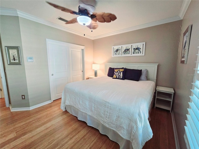 bedroom featuring a ceiling fan, wood finished floors, a closet, crown molding, and baseboards