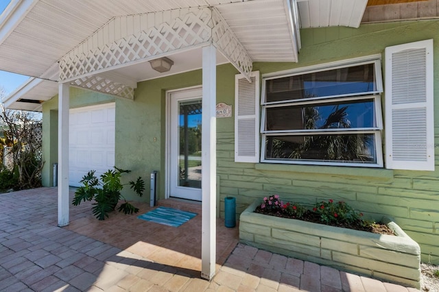 entrance to property with a garage and stucco siding