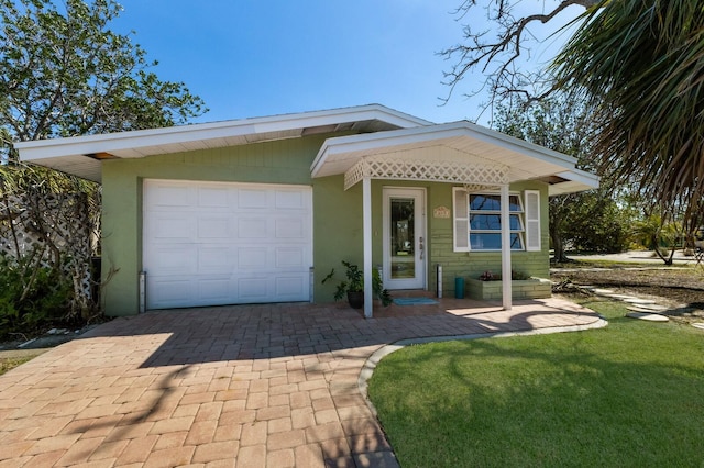 view of front of home with stucco siding, decorative driveway, and a front yard