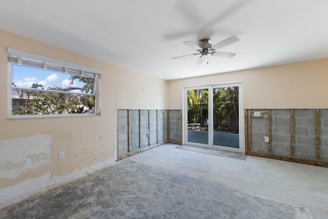 unfurnished room with unfinished concrete floors and ceiling fan