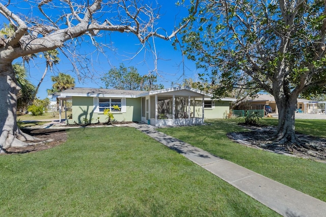 view of front of property featuring a front lawn, a sunroom, and stucco siding