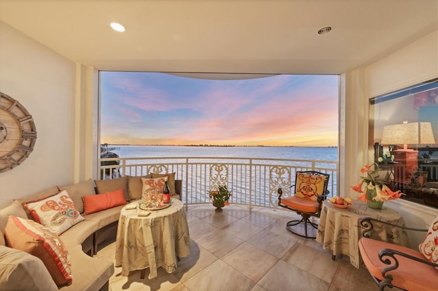 balcony at dusk with a water view and an outdoor hangout area