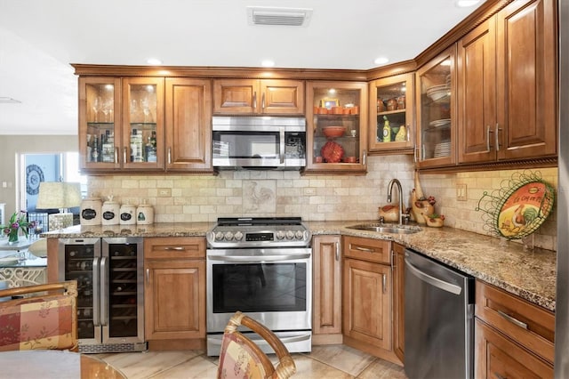 kitchen featuring visible vents, brown cabinets, a sink, wine cooler, and appliances with stainless steel finishes