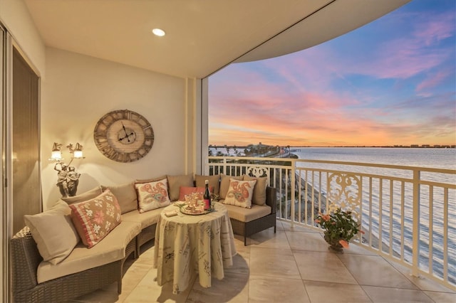 balcony at dusk featuring a water view and an outdoor hangout area