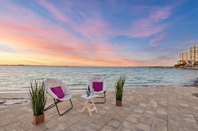 patio terrace at dusk featuring a water view