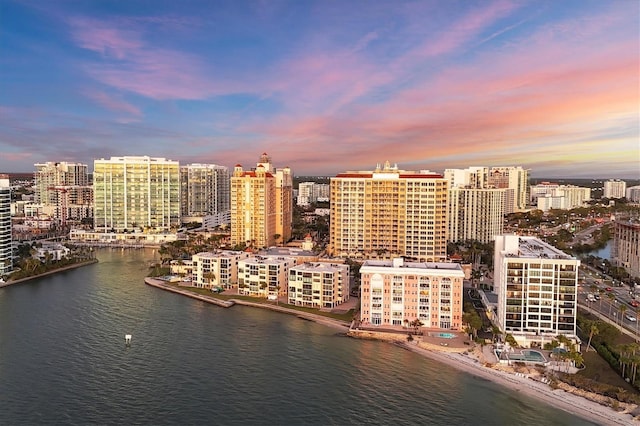 aerial view at dusk featuring a view of city and a water view