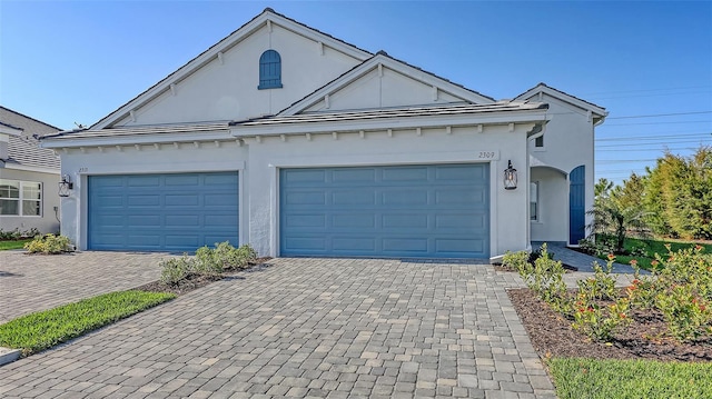 view of front facade featuring decorative driveway, a garage, and stucco siding