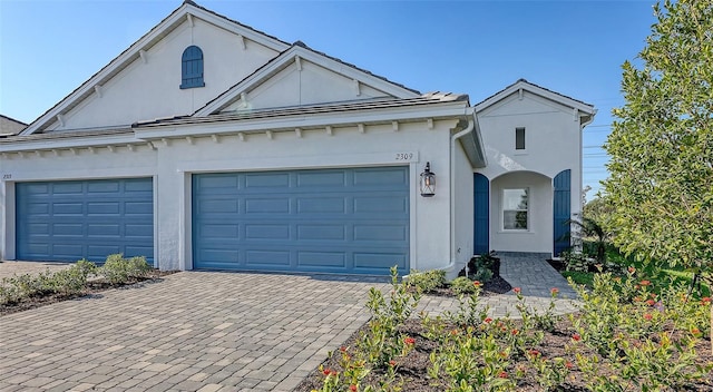 view of front of home with stucco siding, driveway, and a garage