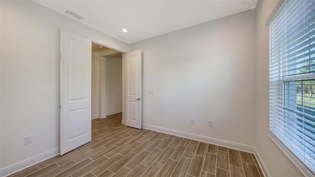 spare room with wood finish floors, visible vents, baseboards, and recessed lighting