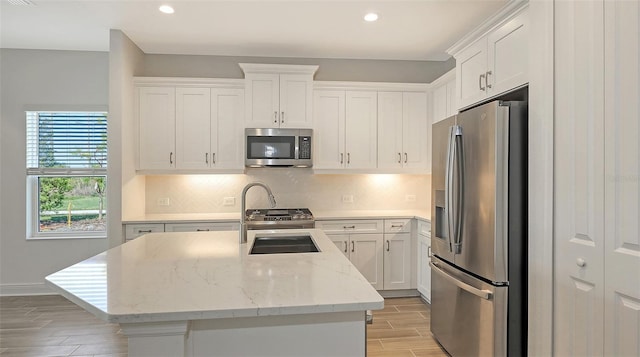 kitchen with a sink, stainless steel appliances, backsplash, and white cabinetry