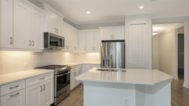 kitchen with white cabinets, tasteful backsplash, appliances with stainless steel finishes, and wood tiled floor