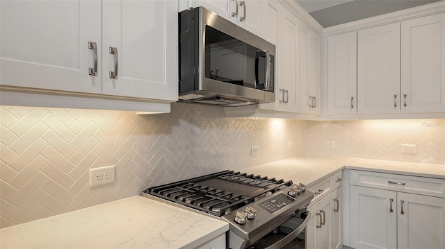 kitchen with white cabinets, backsplash, and stainless steel appliances