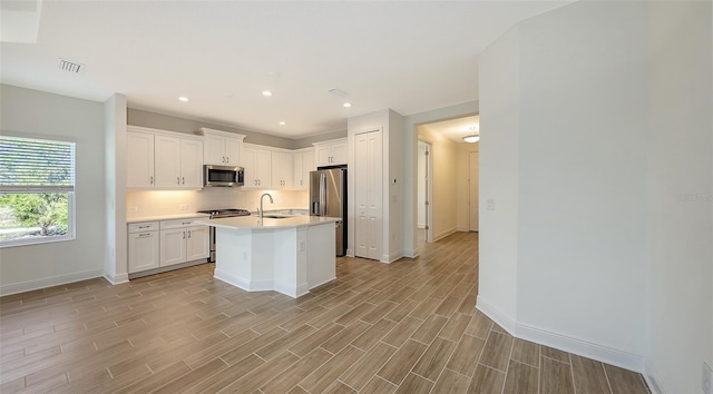 kitchen with visible vents, wood finish floors, a sink, light countertops, and appliances with stainless steel finishes