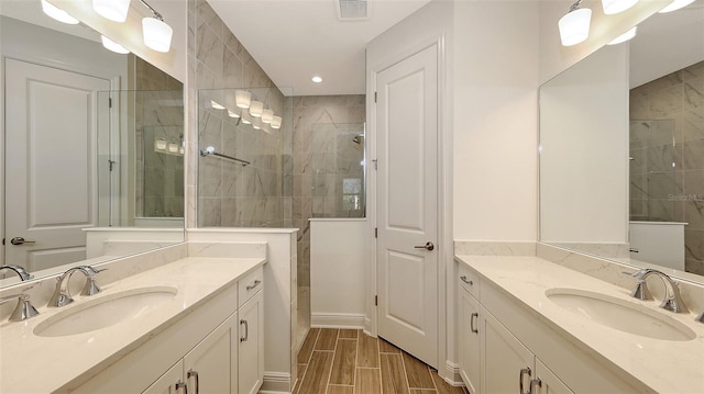 full bathroom with wood tiled floor, two vanities, walk in shower, and a sink