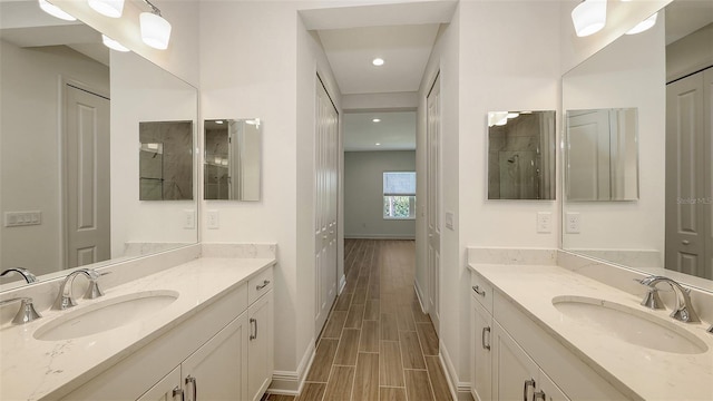 bathroom featuring wood tiled floor, two vanities, and a sink