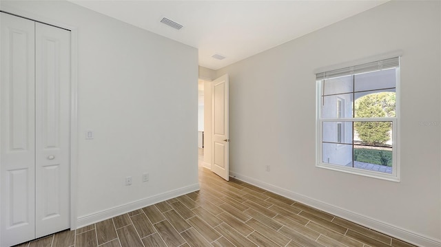 unfurnished bedroom featuring baseboards, visible vents, and wood finish floors