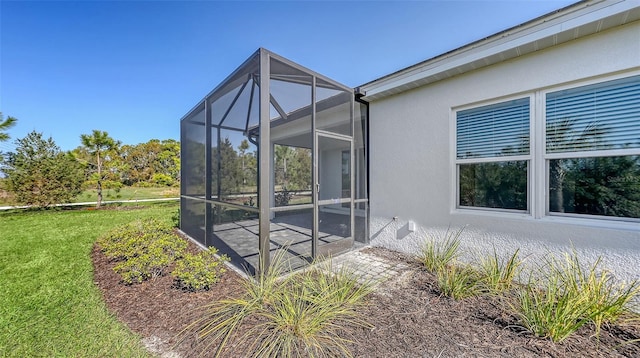 view of property exterior featuring glass enclosure, a lawn, and stucco siding