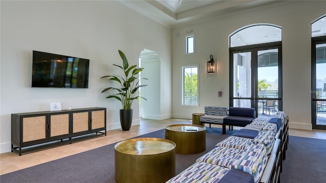 carpeted living area with baseboards, arched walkways, a high ceiling, and ornamental molding
