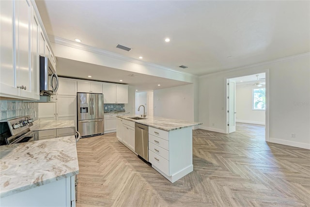 kitchen featuring visible vents, a sink, backsplash, appliances with stainless steel finishes, and baseboards