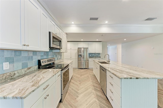 kitchen with visible vents, a sink, backsplash, stainless steel appliances, and white cabinets