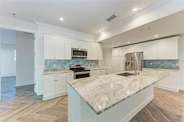 kitchen with a sink, appliances with stainless steel finishes, ornamental molding, and white cabinetry