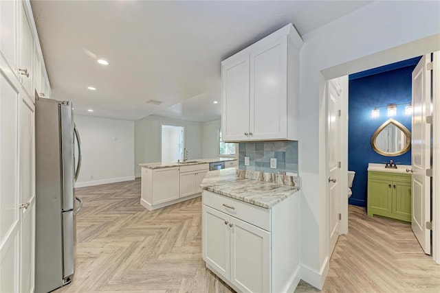 kitchen featuring baseboards, a sink, white cabinets, appliances with stainless steel finishes, and tasteful backsplash