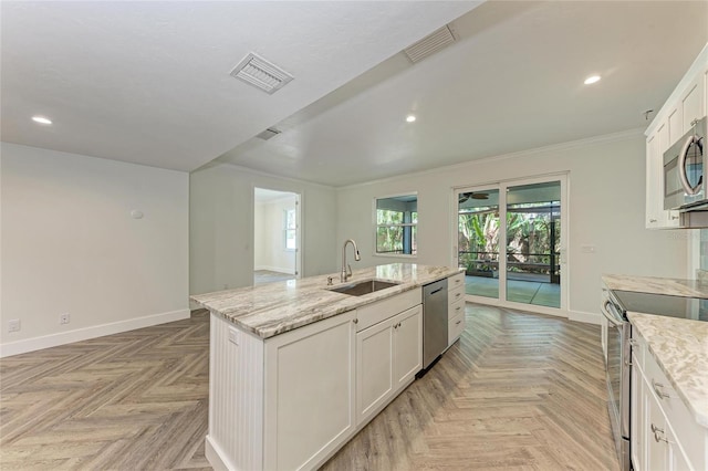 kitchen with a center island with sink, baseboards, a sink, appliances with stainless steel finishes, and white cabinetry