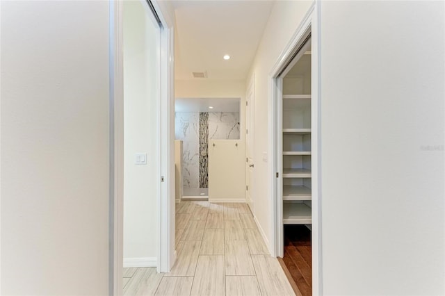 hallway with wood finish floors, baseboards, and recessed lighting