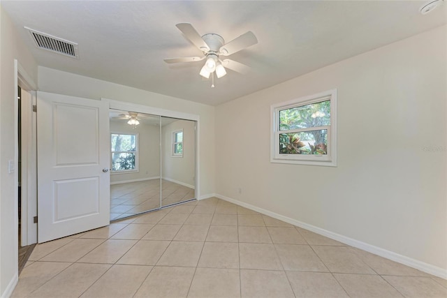 unfurnished bedroom with visible vents, baseboards, light tile patterned floors, a closet, and a ceiling fan