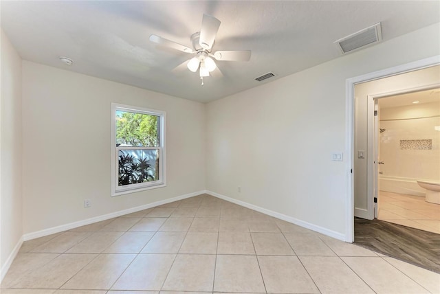 empty room featuring light tile patterned floors, visible vents, baseboards, and ceiling fan