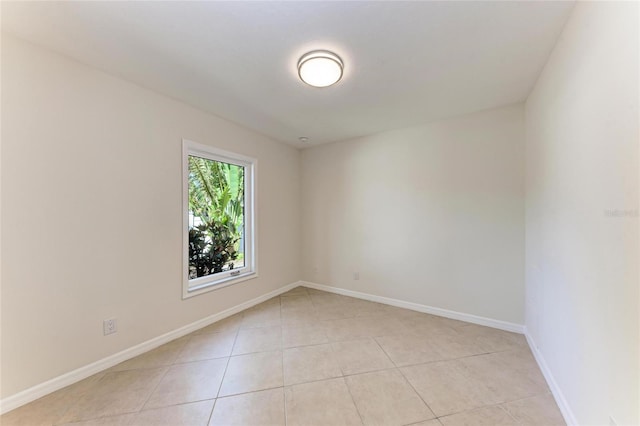 spare room featuring baseboards and light tile patterned flooring