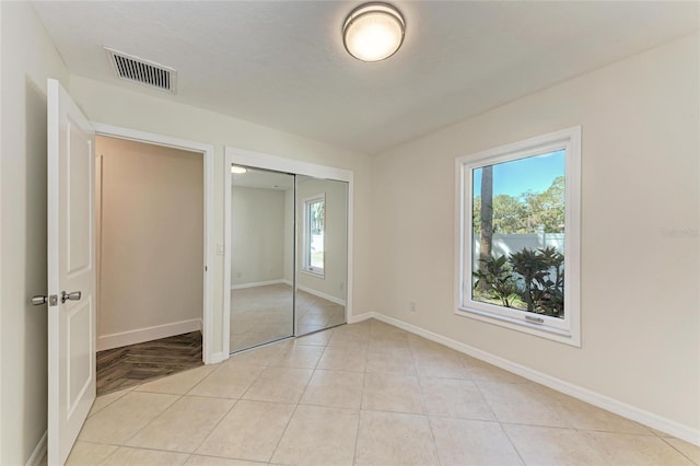 unfurnished bedroom featuring light tile patterned floors, visible vents, baseboards, and a closet