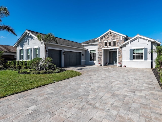 view of front facade featuring decorative driveway, a garage, stone siding, and stucco siding