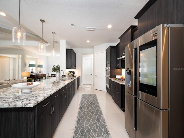 kitchen featuring open floor plan, light tile patterned floors, a peninsula, stainless steel fridge, and a sink