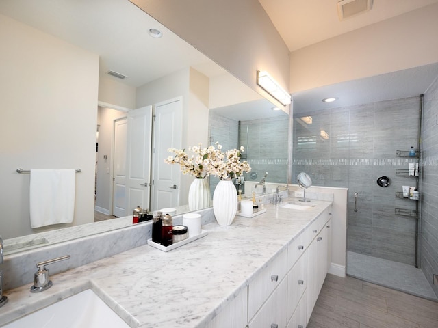 full bathroom featuring a sink, visible vents, double vanity, and a shower stall
