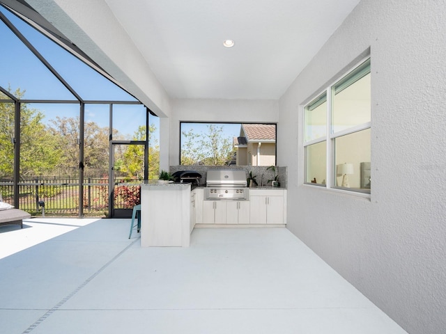 view of patio / terrace featuring glass enclosure, exterior kitchen, and grilling area