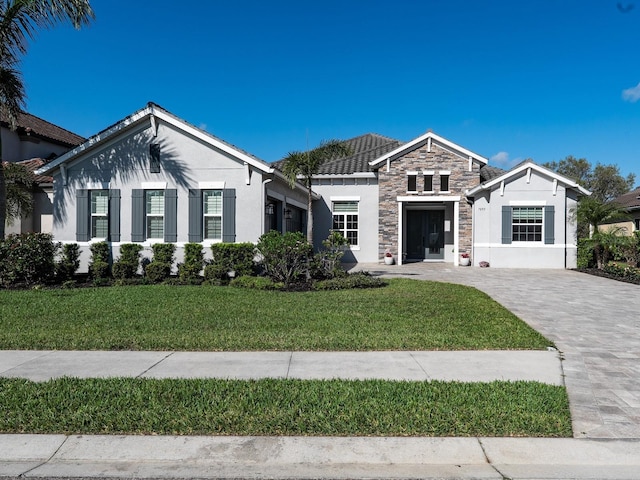 ranch-style house featuring stone siding, stucco siding, decorative driveway, and a front yard