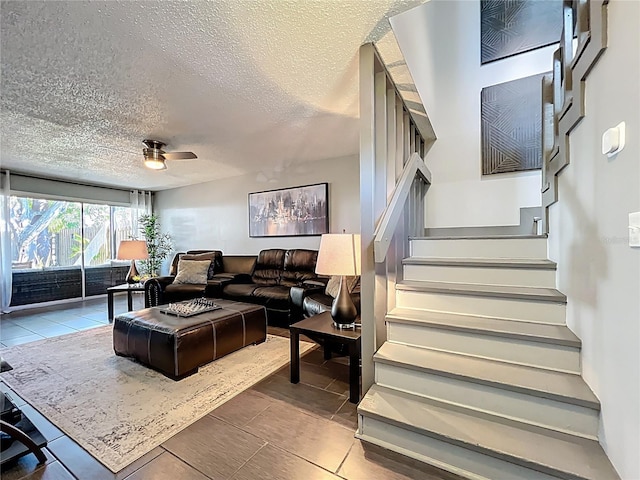 tiled living room featuring stairs, ceiling fan, and a textured ceiling