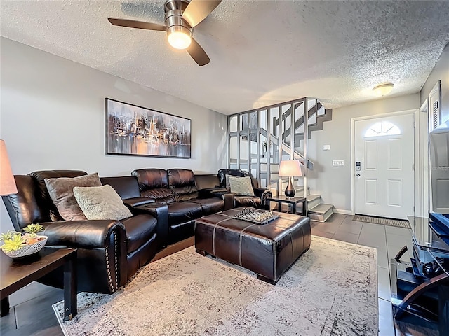 tiled living room with a textured ceiling, stairs, and ceiling fan