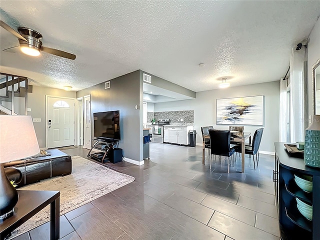 living area with visible vents, a textured ceiling, and a ceiling fan