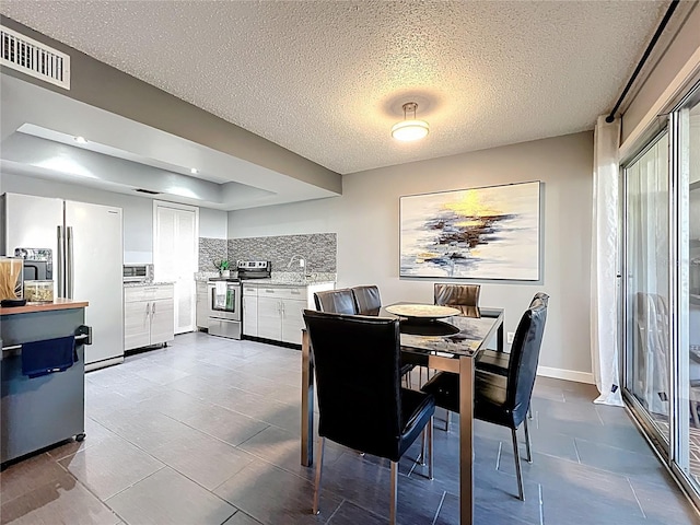 dining space with visible vents, baseboards, a textured ceiling, and a toaster