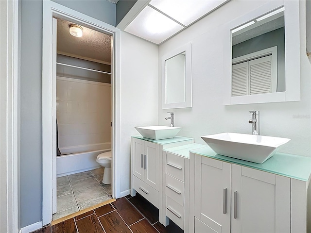 full bathroom featuring a textured ceiling, toilet, wood finished floors, and a sink